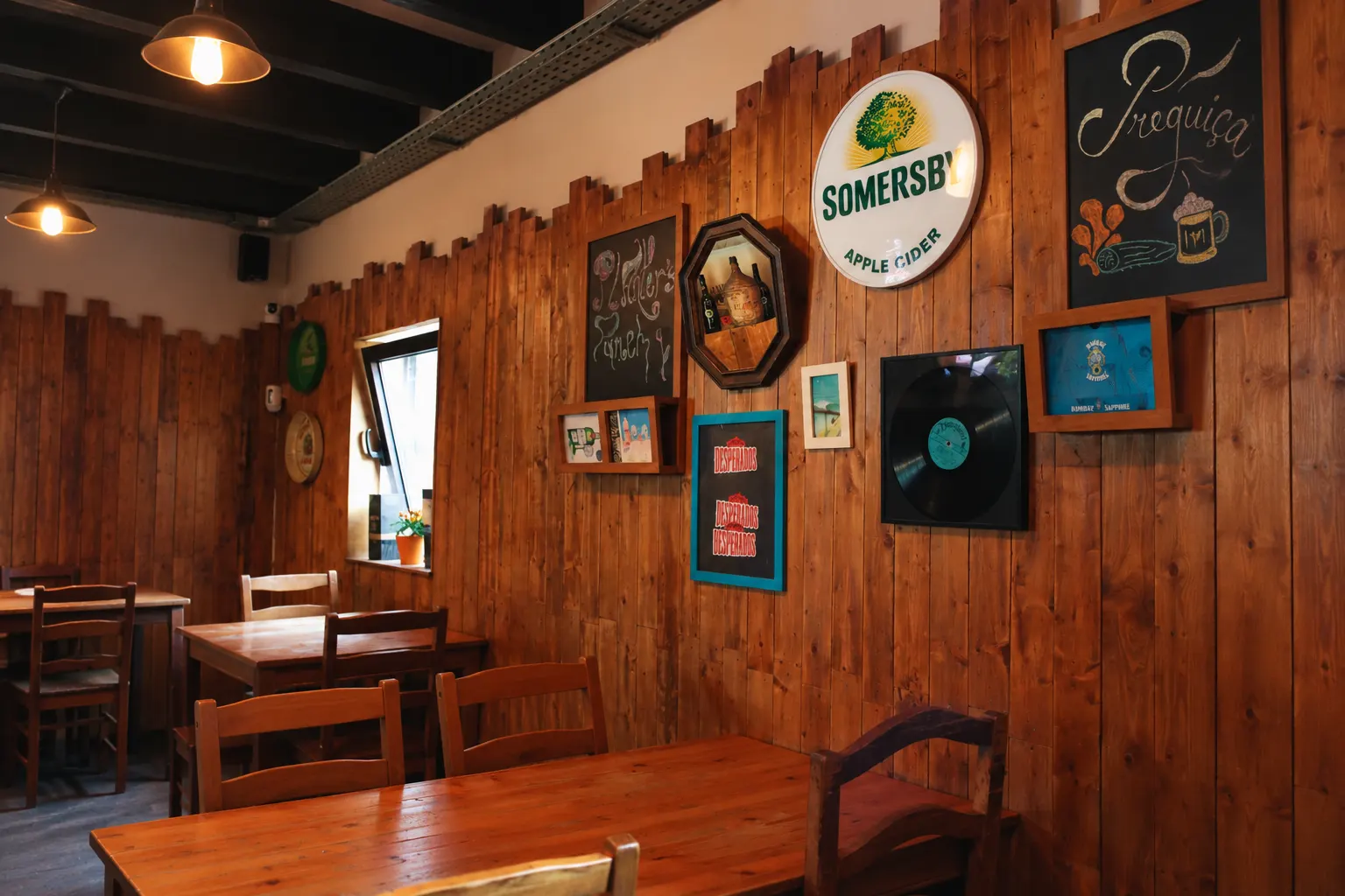 A sala do Café Preguiça: paredes forradas a madeira, quadros antigos, o nome da casa escrito a giz numa ardósia e mesas de madeira.