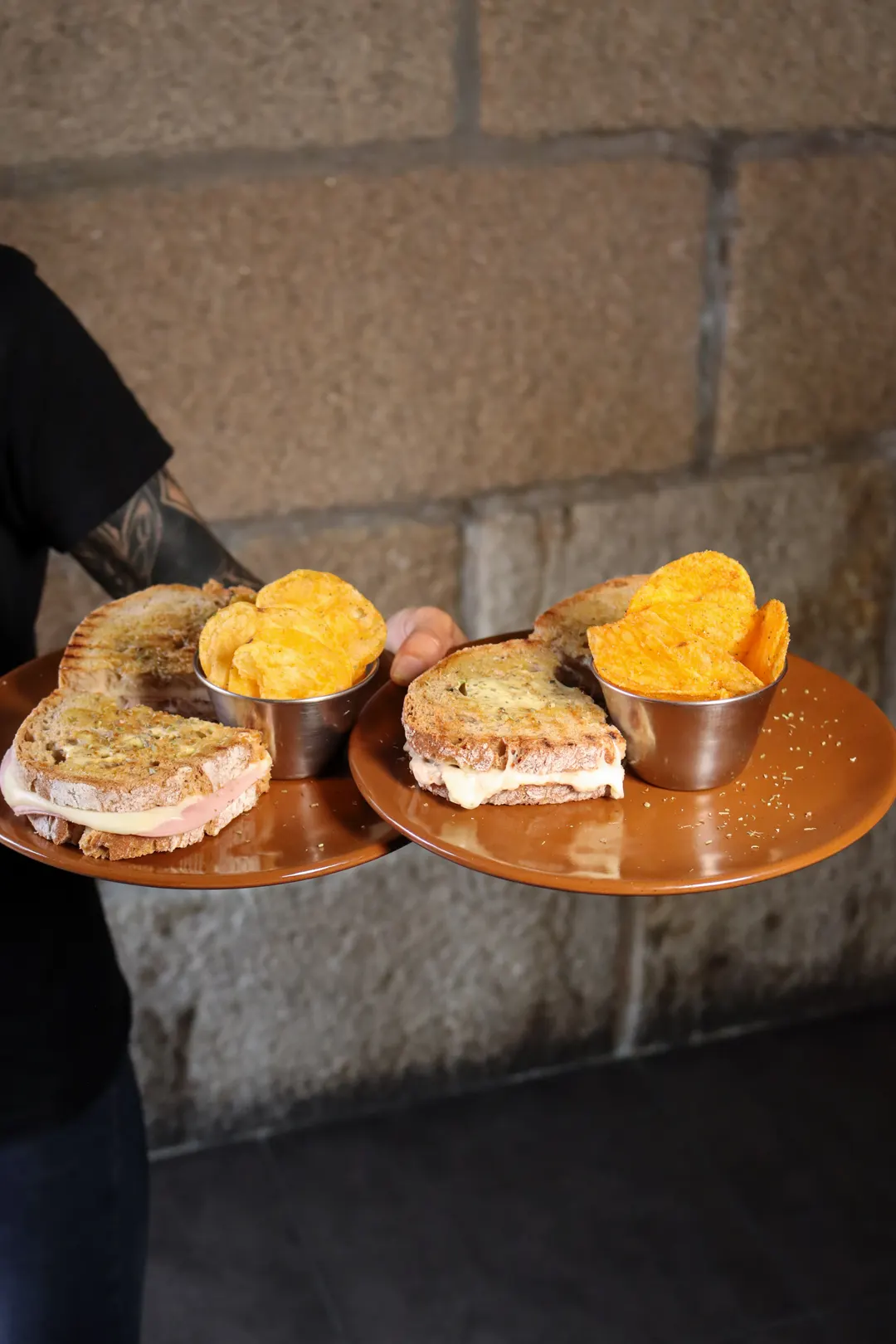 Duas tostas no pão saloio, uma mista e uma de atum, em dois pratos com batata frita.
